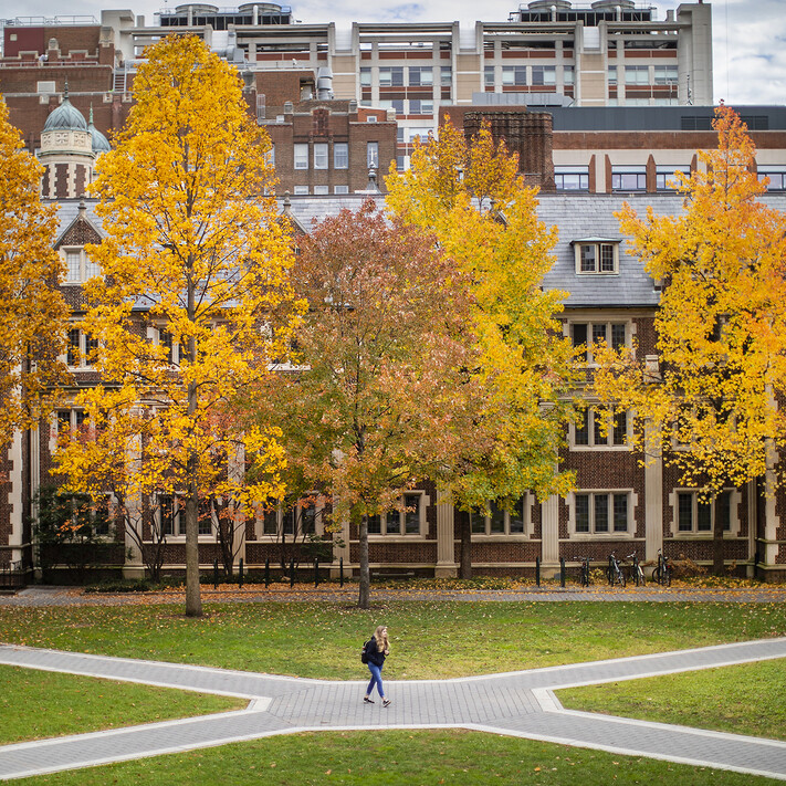 student walking in crossing paths on campus